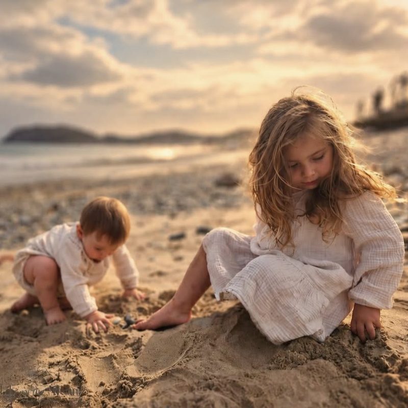 Brother and sister playing in the sand at sunset