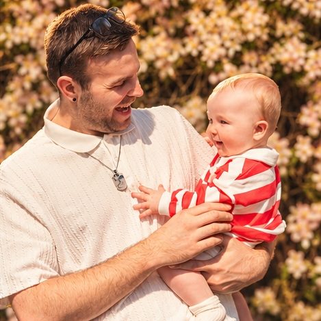 Dad and baby laughing among blossom