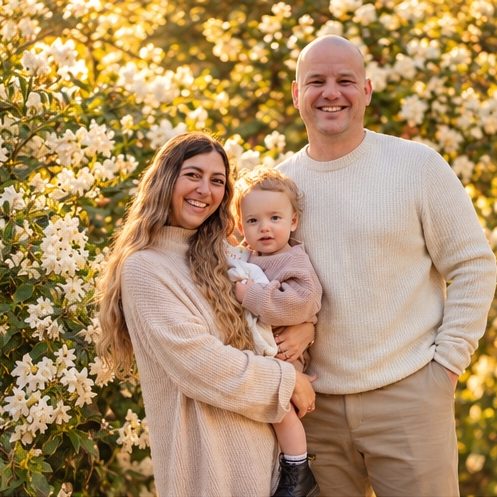 Family of three in front of a blossoming hedge